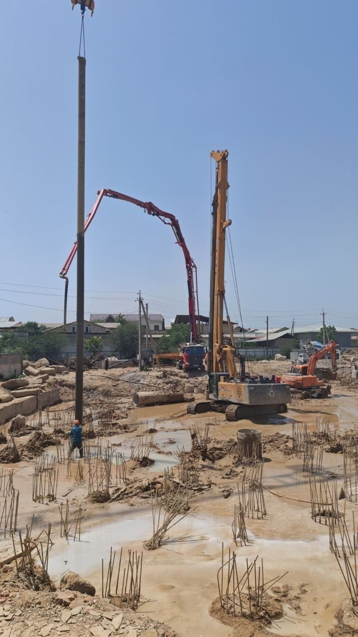 Bored piling rig lifting pile on active construction site